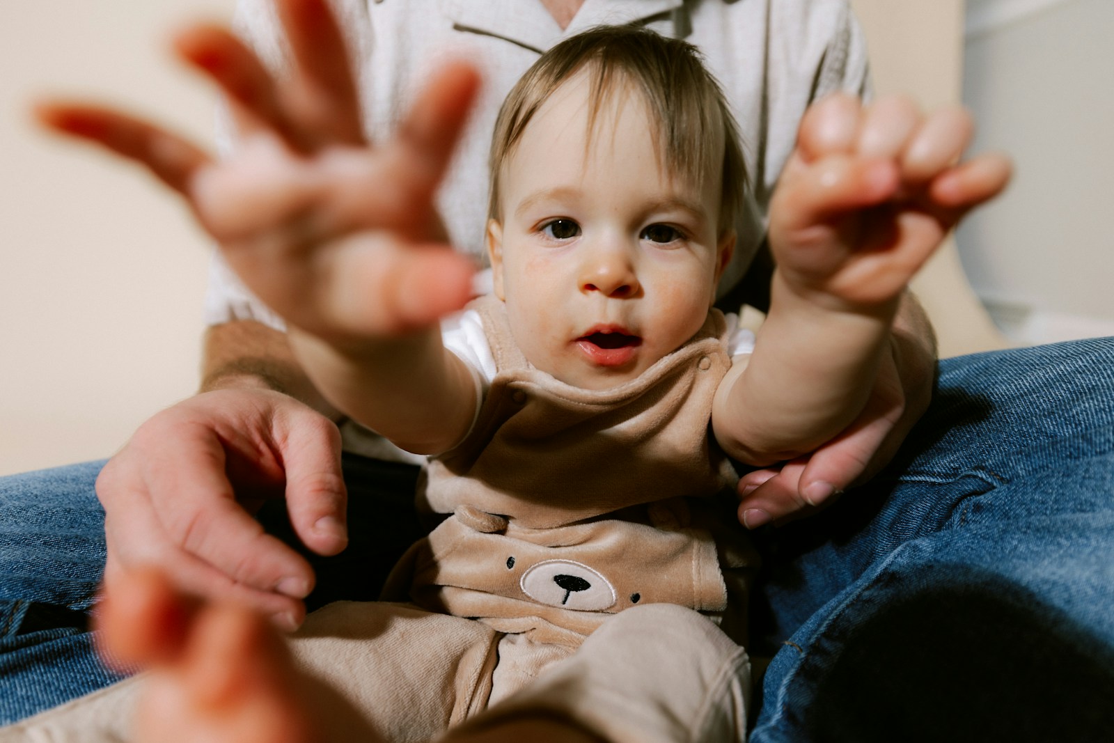 A baby reaching out with hands forward.